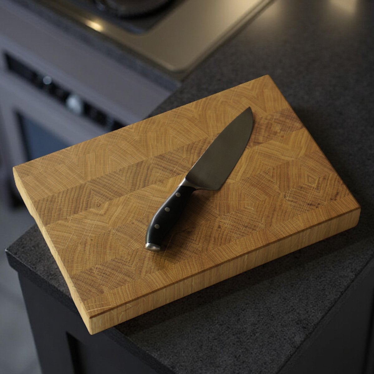 Stirnholzbrett mit Küchenmesser darauf in dunkler Küchenumgebung. SPECHTWERK Manufaktur